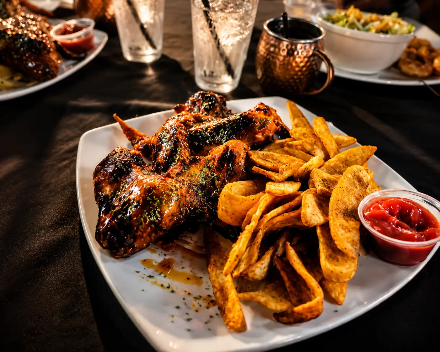 Grilled wings with seasoned potato wedges and ketchup on a dinner table